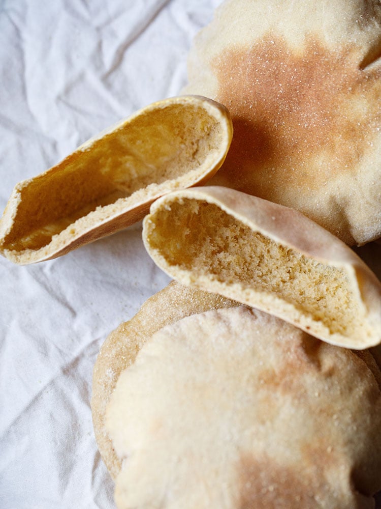 top view of pita bread pockets with three pita bread thrown around on a crumpled white cotton napkin