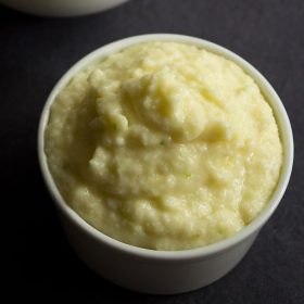 raw mango chutney in white bowl on a black backdrop.