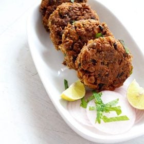 shami kabab served on a white platter with onion slices and lemon wedges.