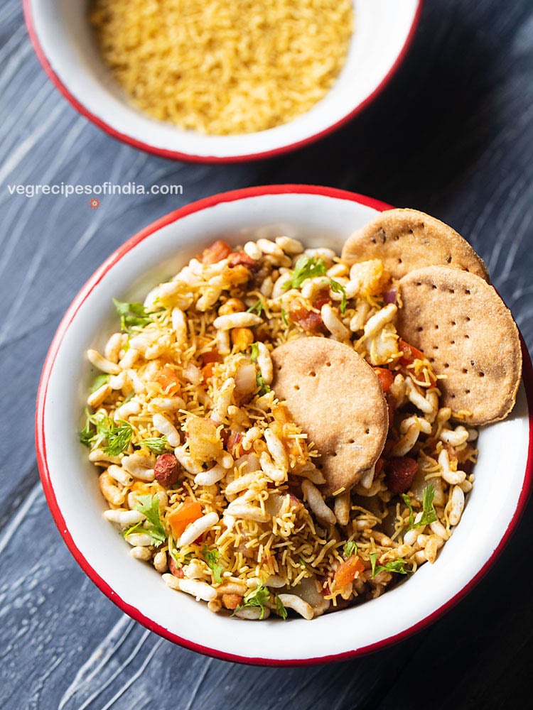 bhel puri served with a side of crisp baked puri in a red rimmed white bowl