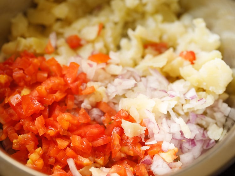 chopped onions, tomatoes and boiled potatoes in a large steel bowl