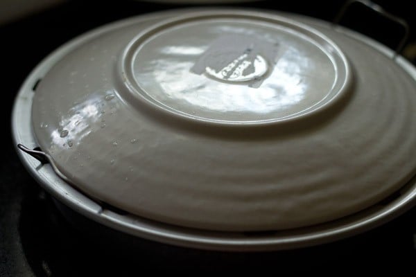 inverted plate on top of the pan with the steamed khaman