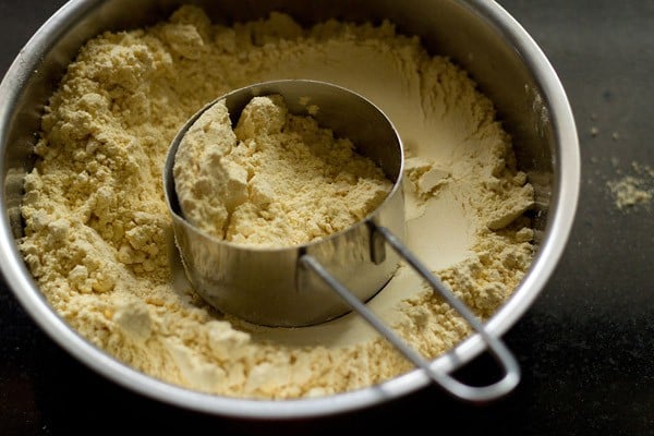 besan with a measuring cup in a mixing bowl