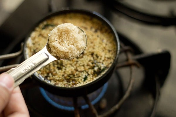 sugar being added with a measuring spoon