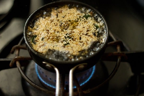 tempering mixture of oil, water, spices and herbs simmering on a lit stove-top