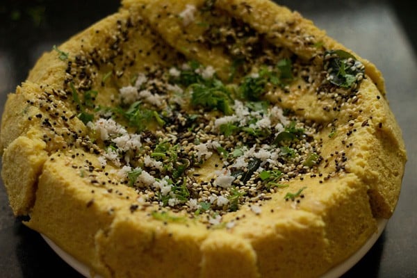 khaman dhokla garnished with coconut and coriander leaves