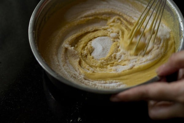 eno being mixed in the besan batter with a wired whisk