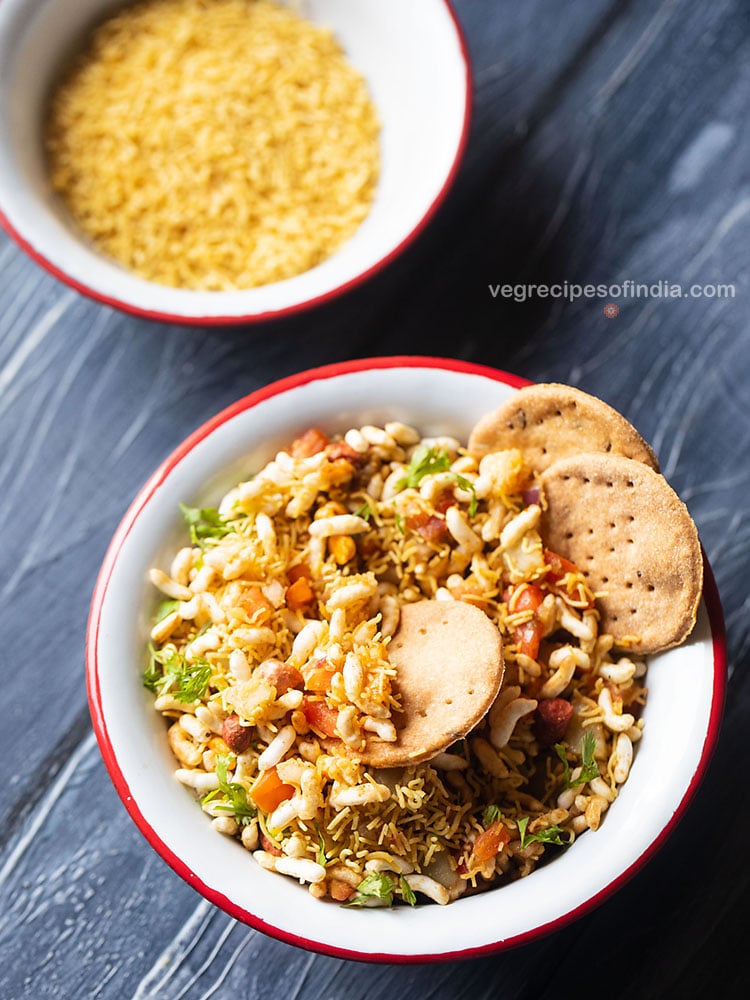 bhel puri served with a side of crisp baked puri in a red rimmed white bowl