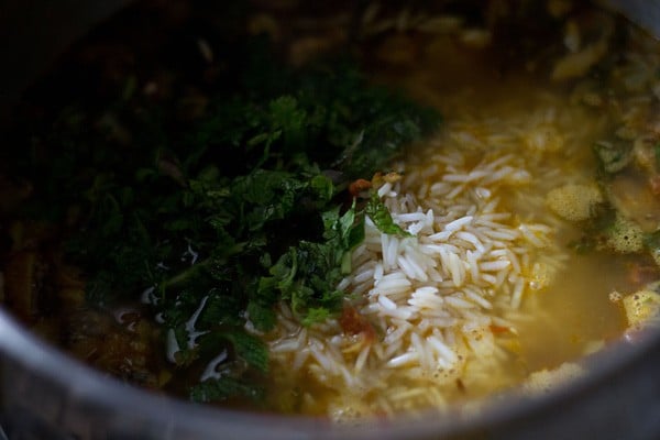 herbs added on top of rice in pan