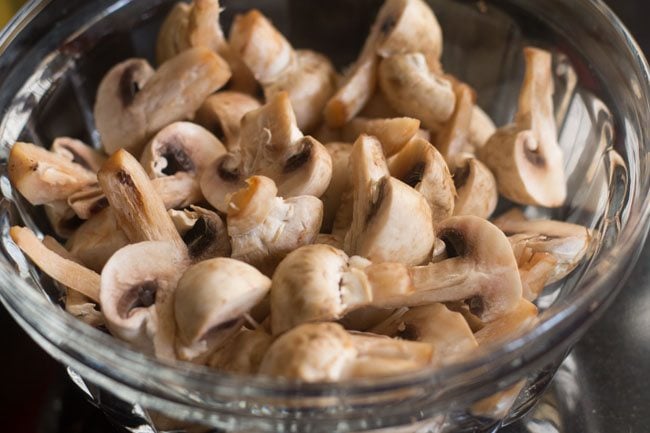 quartered button mushrooms in a prep bowl.