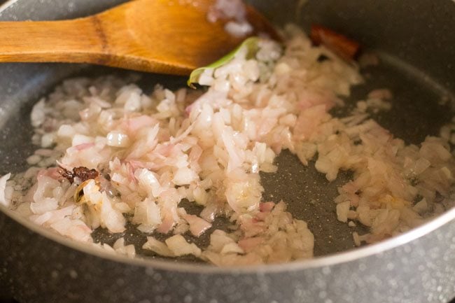 wooden spoon stirring the onions as they continue to cook.