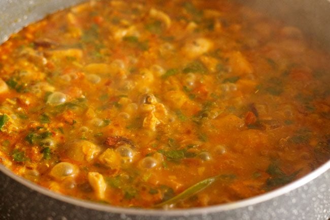 mushroom methi recipe is bubbling on the stove and looks well cooked.