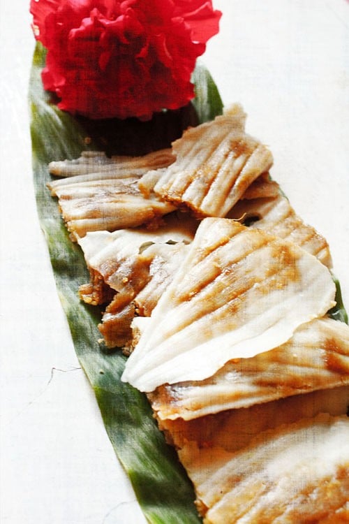 patholi Goan recipe patoleo served on a fresh turmeric leaf with a hibiscus flower kept on the top end.