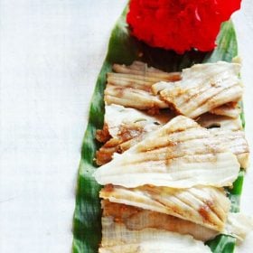 patoli served on a fresh turmeric leaf with a hibiscus flower kept on the top end.