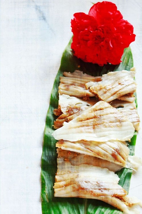 patoli served on a fresh turmeric leaf with a hibiscus flower kept on the top end.