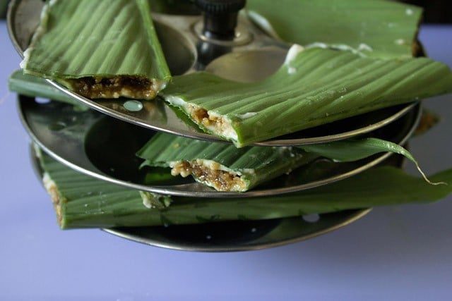 patholi-recipe8 prepared stuffed turmeric leaves placed on an idli steamer rack.