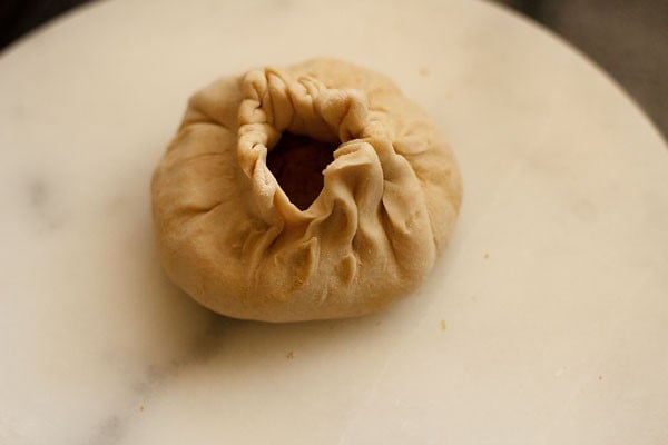 dough is wrapped around puran mixture and looks like a purse or knapsack