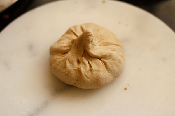 top of poli dough is pinched shut around puran mixture, leaving a shape that looks like a head of garlic