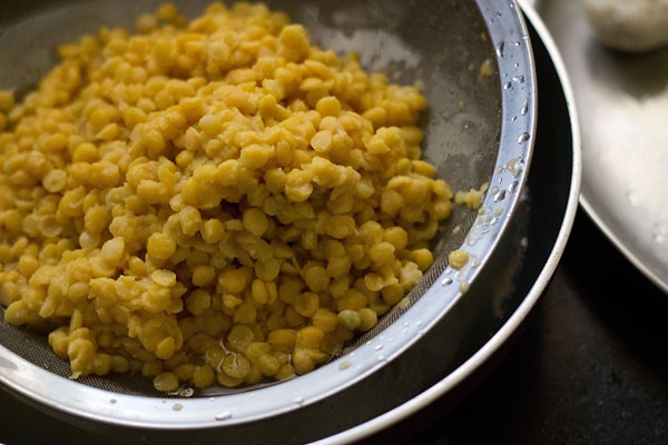 straining cooked chana dal for making puran poli recipe