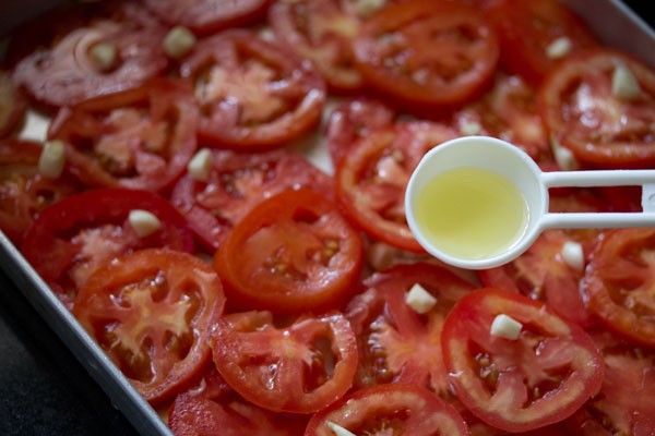 drizzling olive oil over tomatoes and garlic.