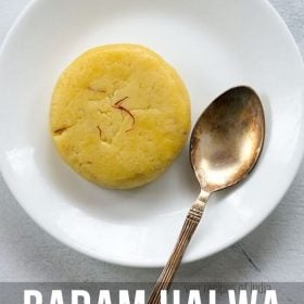 badam halwa served on a white plate with a brass spoon by the side and text layovers.