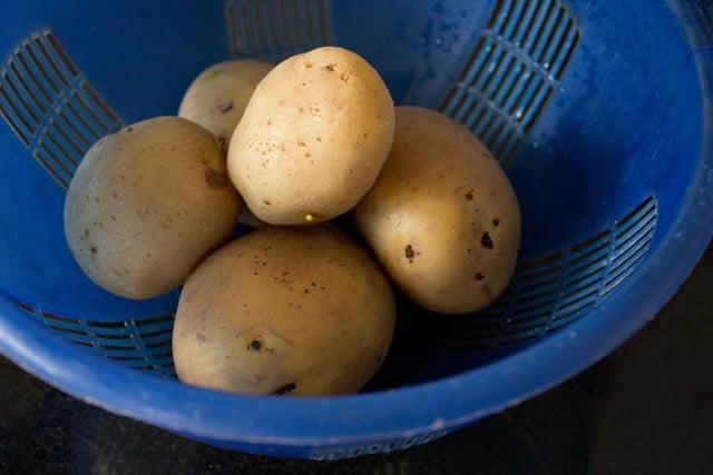 parboiled potatoes in a blue colander.