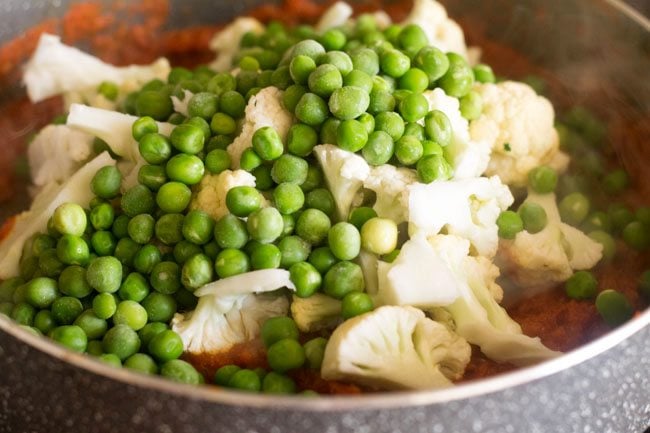 adding cauliflower florets and green peas to pan