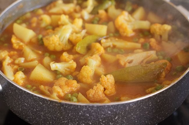 boiling aloo gobi matar curry in pan 