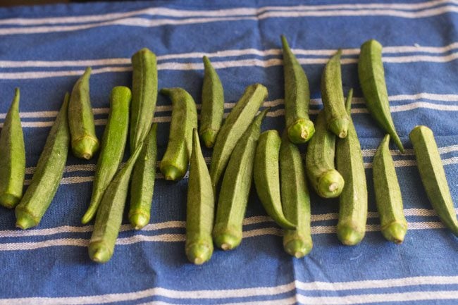 drying okra on a kitchen napkin to make  bhindi ki sabji