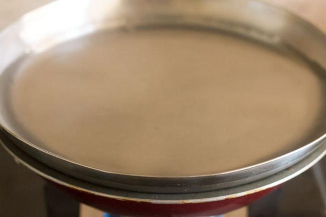 cooking bhindi sabji covered with a rimmed lid with water in it