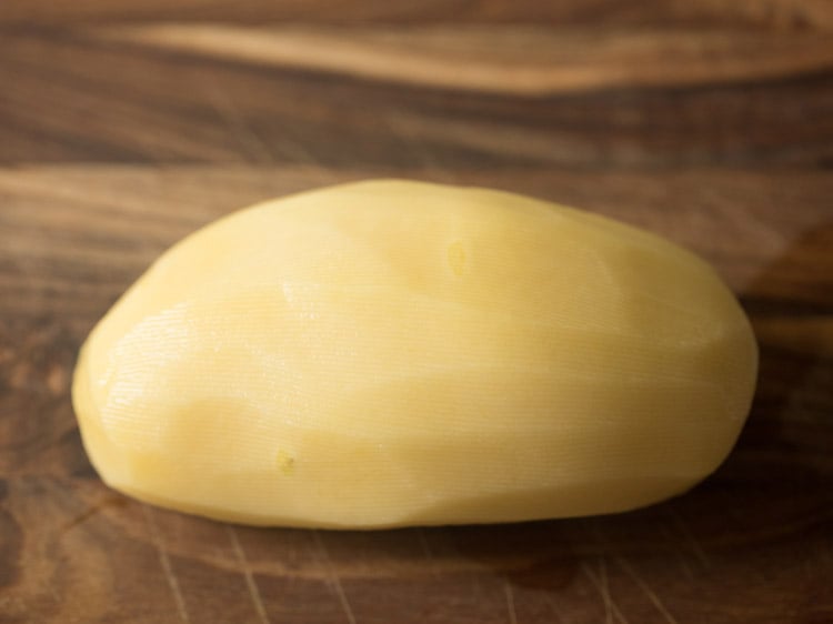 peeled potato on a wooden cutting board