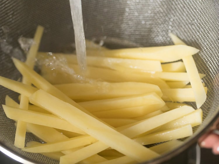 rinsing potato sticks with water in sieve