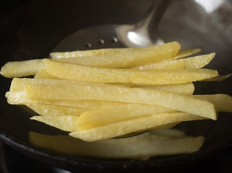 first fry french fries being removed from oil to drain