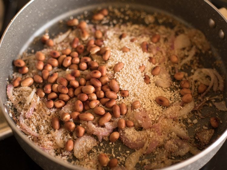 adding roasted peanuts and roasted sesame seeds to the mixture in pan