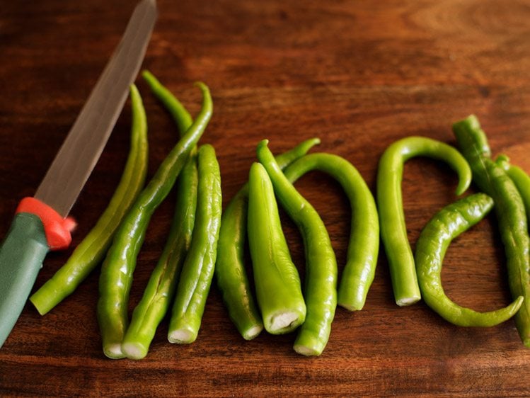 slitting the green chilies vertically, without breaking them