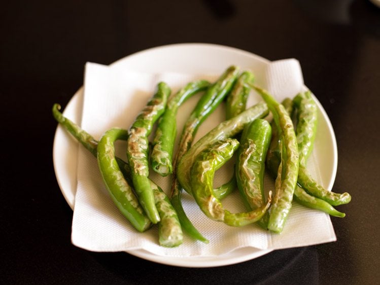 draining fried green chilies on kitchen tissues 