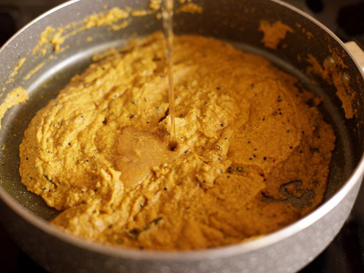 adding tamarind pulp and water to masala paste in pan