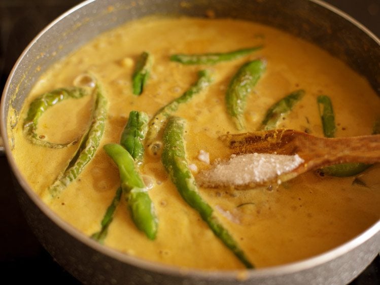 adding salt to masala curry mixture in pan