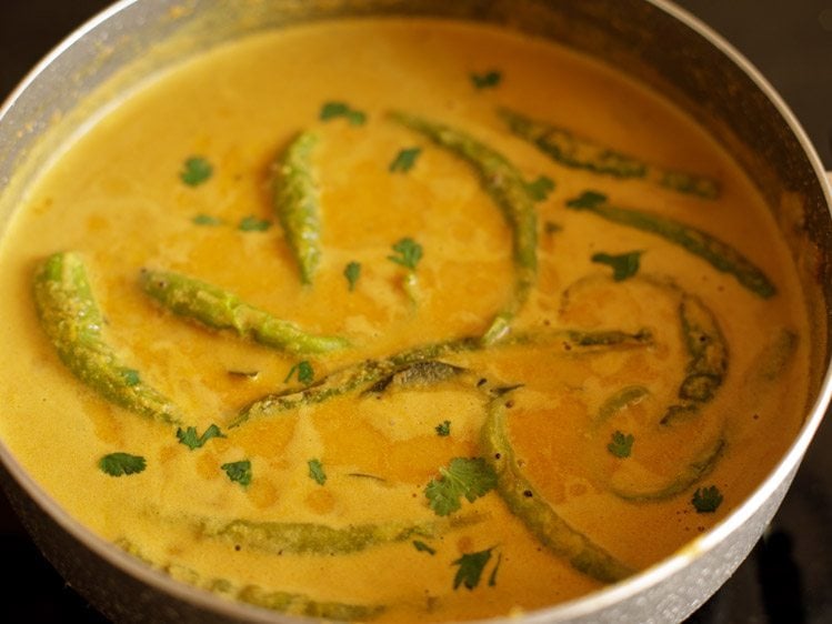 garnishing the curry with coriander leaves