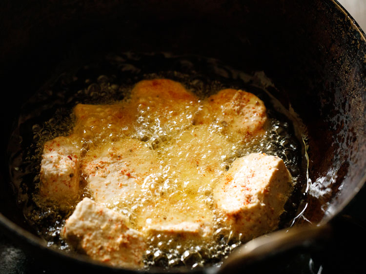 frying paneer cubes in oil in a pan