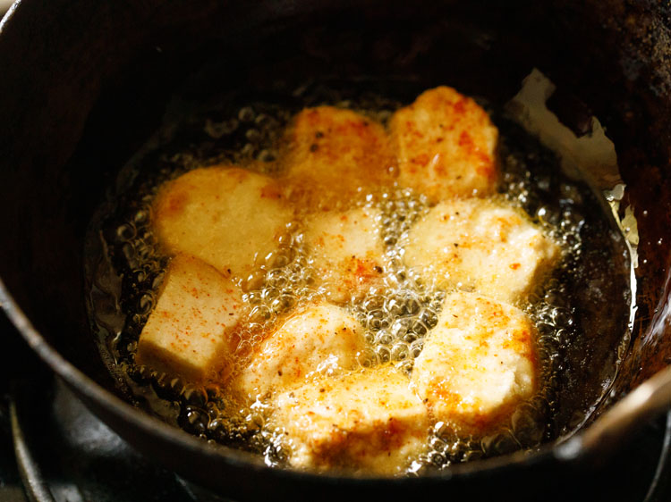 frying paneer cubes in oil in a pan