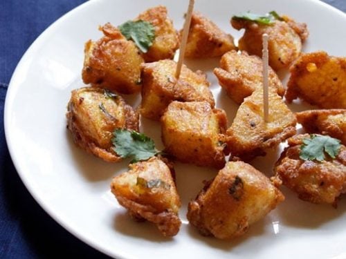 aloo 65 on a white plate garnished with mint and with a few toothpicks on them