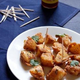 aloo 65 on a white plate garnished with mint and with a few toothpicks on them