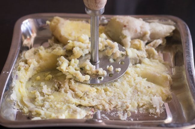 mashing sweet potatoes with a potato masher. 