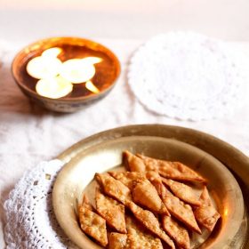 namak para on a brass plate with small lighted lamps placed behind
