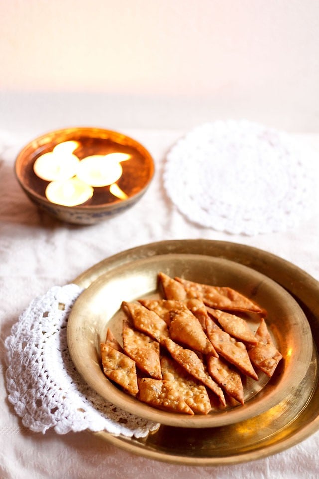 namak para on a brass plate with small lighted lamps placed behind