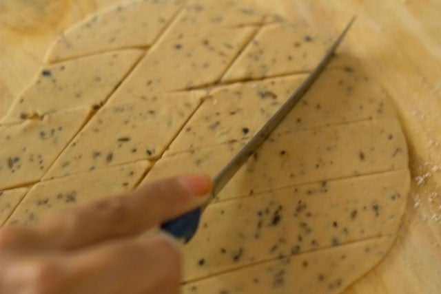 rolled dough being cut with a knife to make diamond cuts