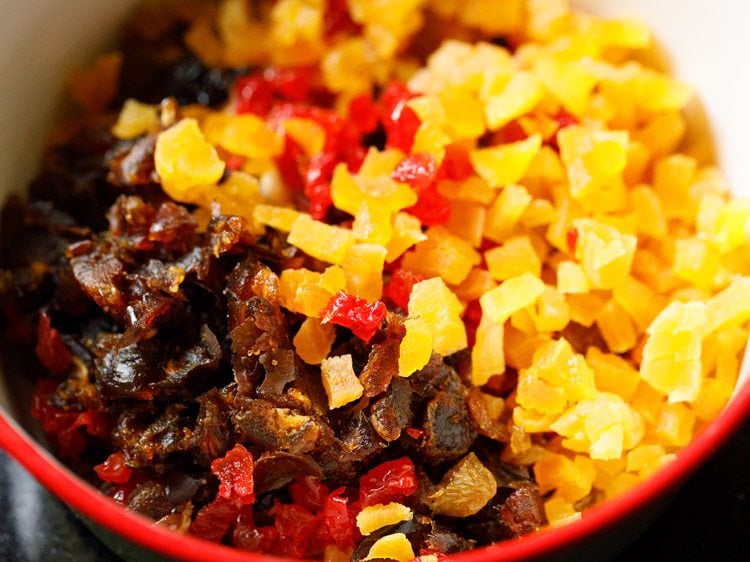 nuts and dried fruits added in a bowl with a red rim.
