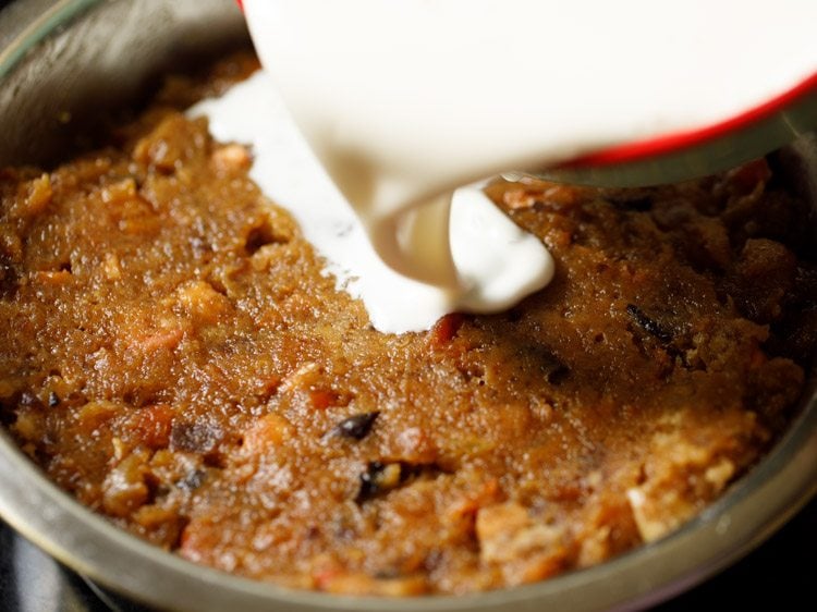 pouring milk mixture in the rough mix of fruit cake batter.