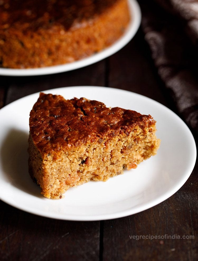 a thick triangular slice of fruit cake served on a white plate.